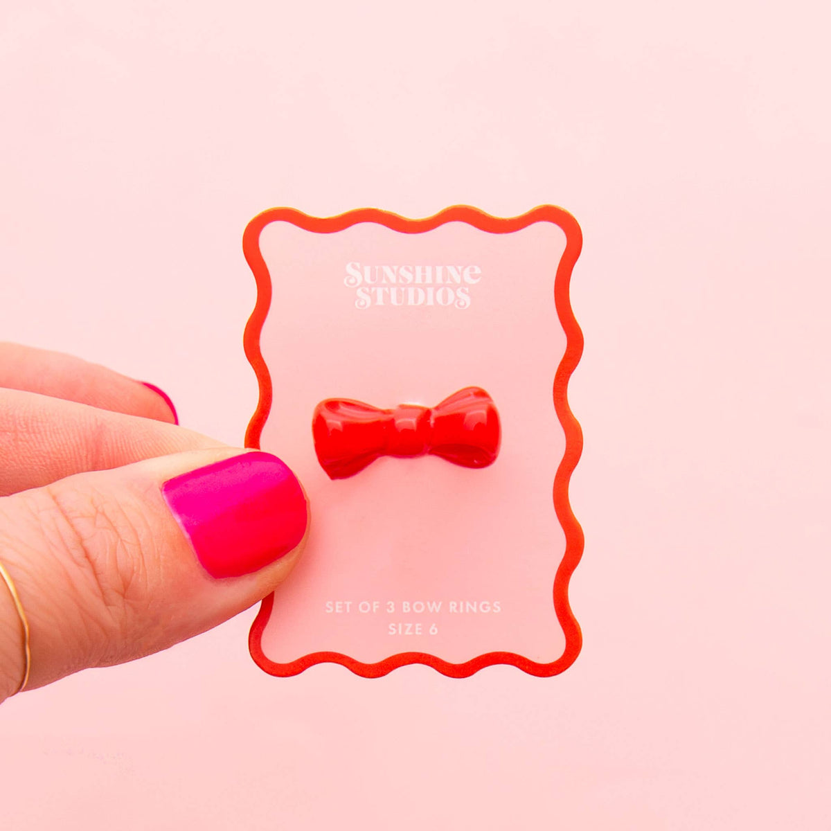 Red Kitsch Bow Ring by Sunshine Studios, featuring a shiny bow design on a silver band, close-up view of the jewelry.