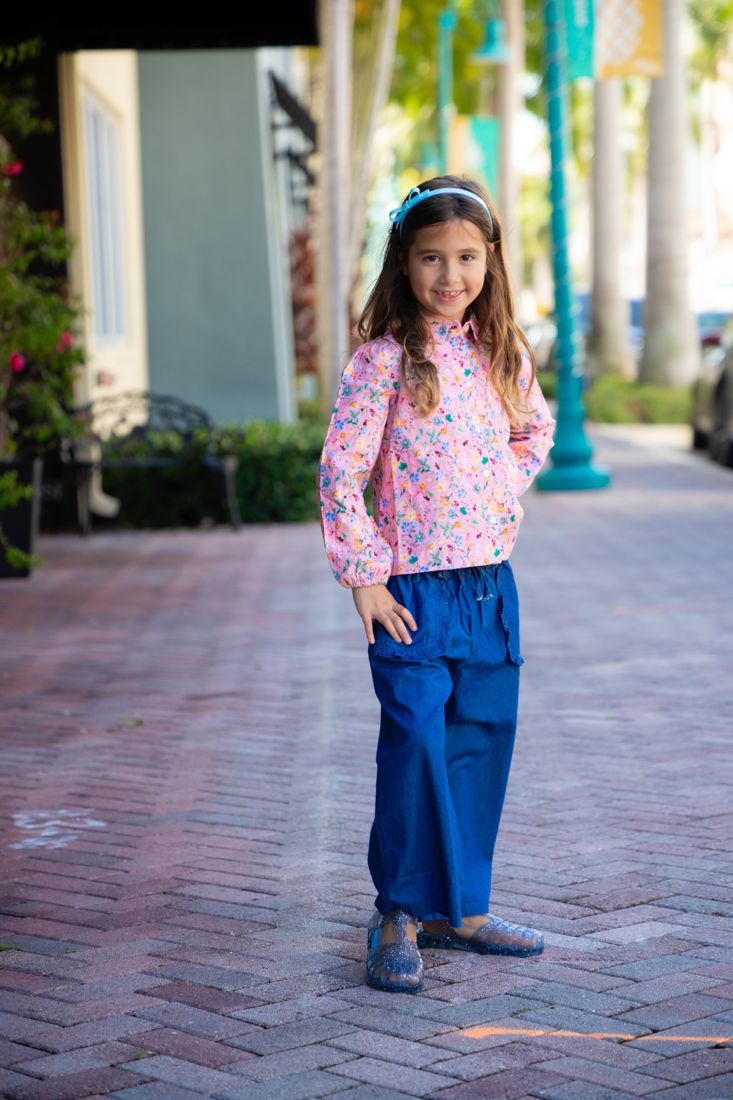 Girl in a pink floral top and wide-leg jeans on a Delray Beach sidewalk
