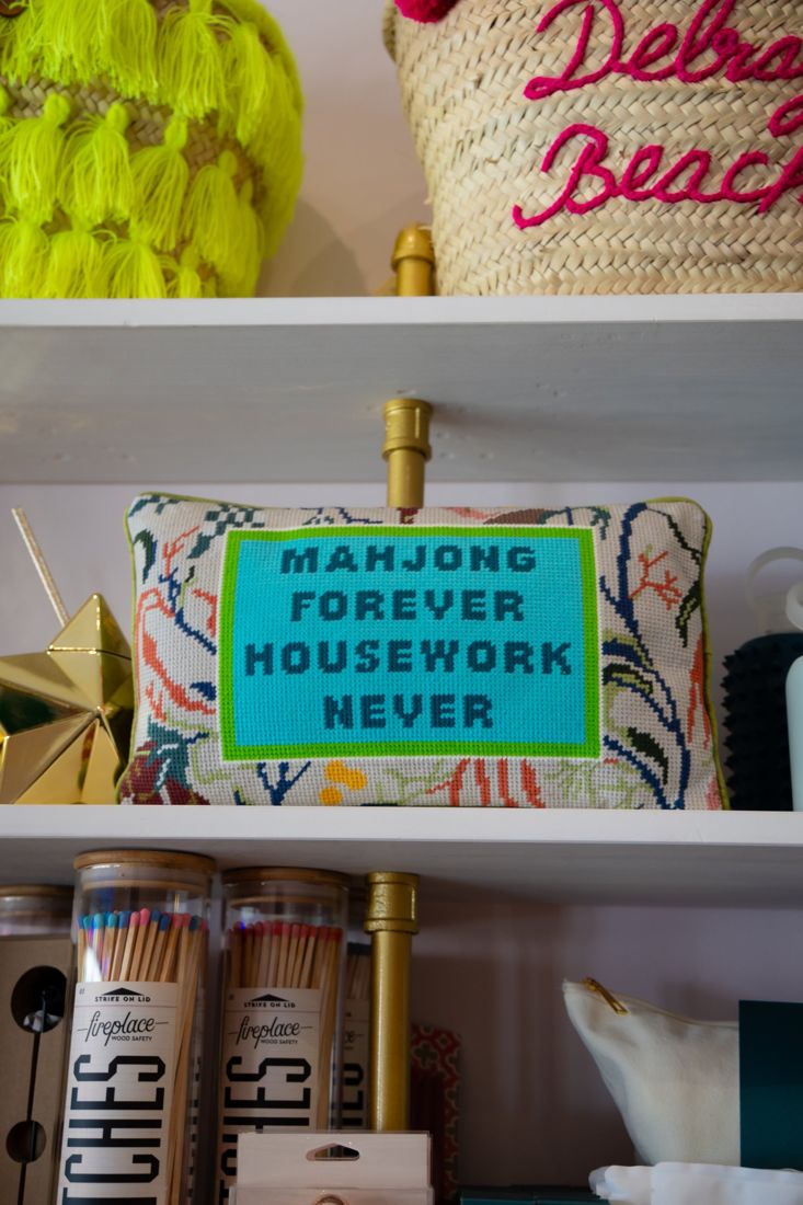 Shelf with a Mahjong Forever needlepoint pillow and gifts for her