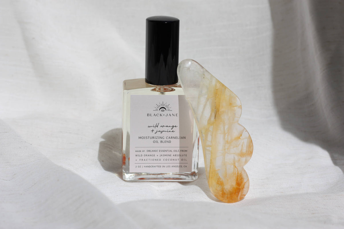 Black + Jane Citrine Gua Sha and crystal facial oil duo for facial massage and skincare, displayed on a neutral background.