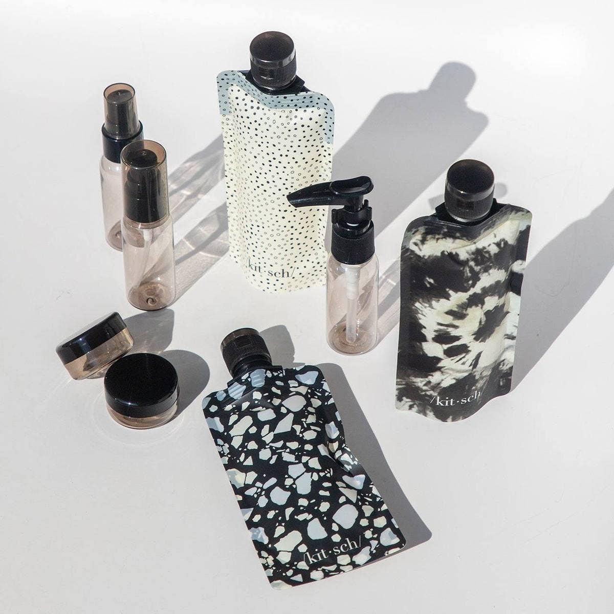 KITSCH Refillable Ultimate Travel 11-piece set in black and ivory with bottles, jars, and accessories for organized travel storage.