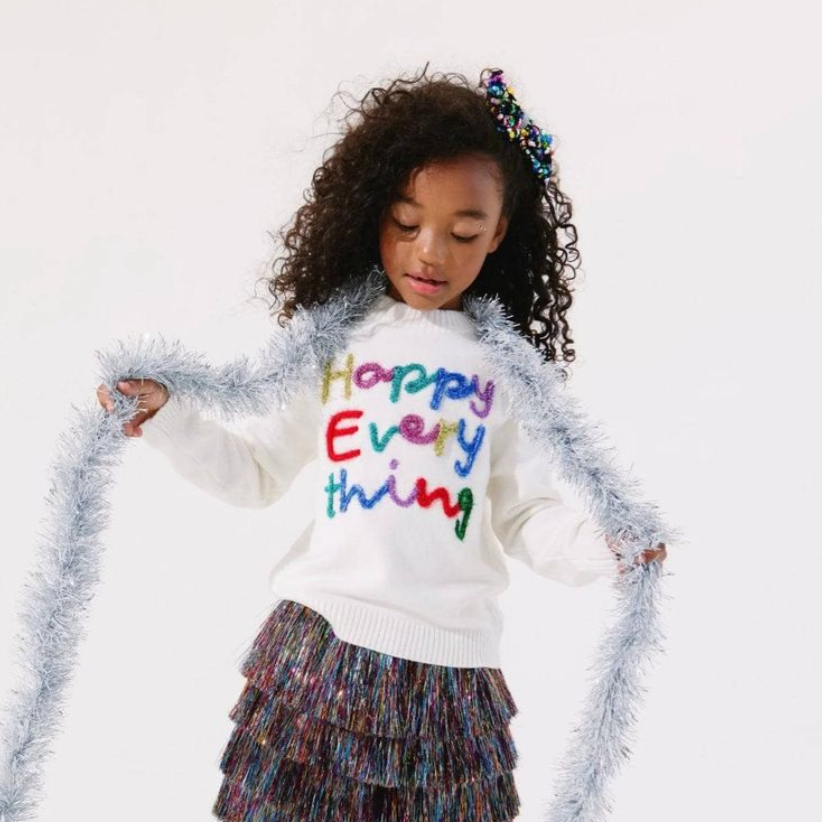 Girl wearing the Happy Everything tinsel sweater with silver tinsel