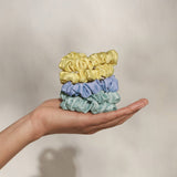 Set of five KITSCH ruched satin scrunchies in various colors, shown in a close-up image highlighting the soft, shiny fabric.
