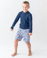 Baby boy navy long sleeve rash guard by RuffleButts + RuggedButts, featuring blue fabric and comfortable fit for infants.