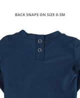 Baby boy wearing navy long sleeve rash guard by RuffleButts + RuggedButts, showing blue sun protection swimwear for infants.