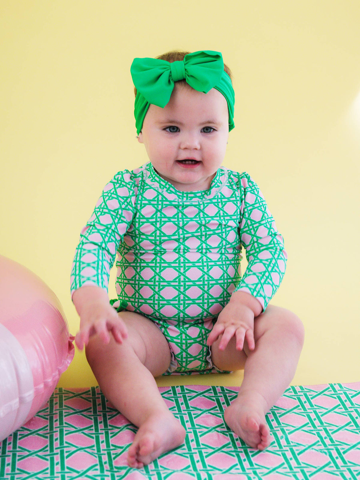 Baby girl pink coastal cane long sleeve rash guard swimsuit with signature rear ruffles, from RuffleButts + RuggedButts, for infants.