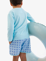 Boys periwinkle blue coastal cane performance hybrid dolphin hem swim trunks by RuffleButts + RuggedButts, shown on a child.