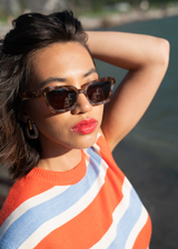 Sardine Demi Bella Vista sunglasses with round frames and tinted lenses, stylishly displayed outdoors.