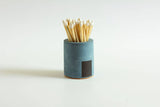 Black and rainbow cylinder match holder by Tenn Prairie, featuring a sleek, colorful design for storing matches safely.