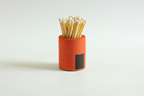 Black and rainbow-colored cylinder match holder by Tenn Prairie, featuring a sleek design for storing matches safely.