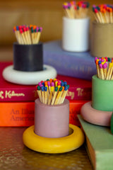 Black and rainbow-colored cylinder match holder by Tenn Prairie with a sleek, modern design for safe match storage.