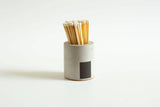 Black and rainbow-colored cylinder match holder by Tenn Prairie with a sleek, modern design for safe and stylish match storage.
