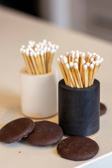 Black and rainbow-colored cylinder match holder by Tenn Prairie, with a sleek, modern design and a secure lid for storing matches.