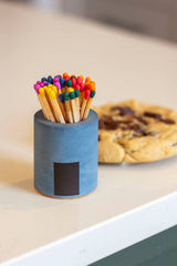 Black and rainbow-colored Cylinder Match Holder by Tenn Prairie, featuring a sleek cylindrical design for safe match storage.