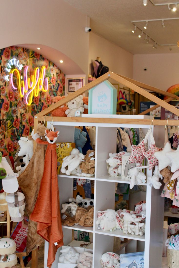Wooden house-shaped shelves filled with baby gifts and soft toys