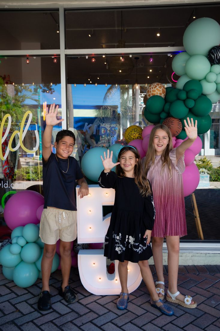 Kids waving outside the A Little Wyld shopfront with balloons